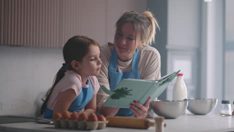 woman-and-her-little-daughter-are-reading-cookbook-kitchen-of-house-in-sunday-mother-is-teaching-her-child-to-cook